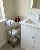 Rolling storage cart beside a bathroom sink